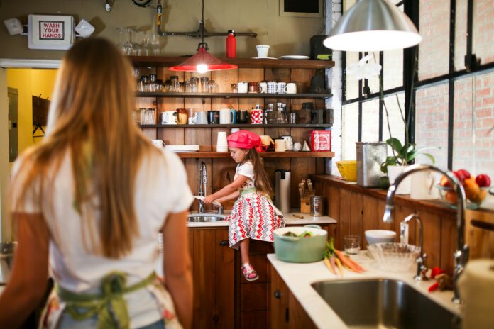 Person cleaning kitchen appliances, wiping down oven and microwave surfaces for a spotless, well-maintained kitchen.