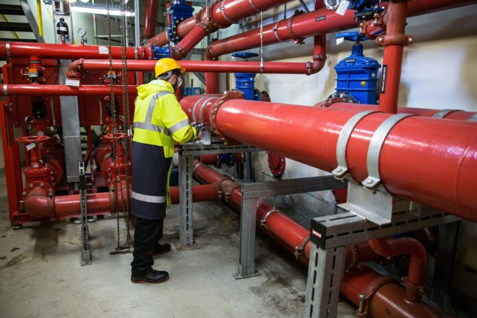 Illustration of a homeowner performing plumbing system maintenance, including checking for leaks, inspecting pipes, and testing water pressure for efficiency.