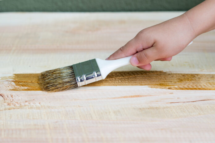 Wood staining process for beginners: a close-up of hands applying stain to a wooden surface