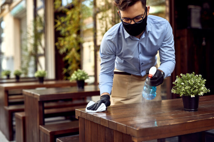 A homeowner performing DIY deck maintenance by cleaning, staining, and inspecting wooden deck boards for long-lasting durability.