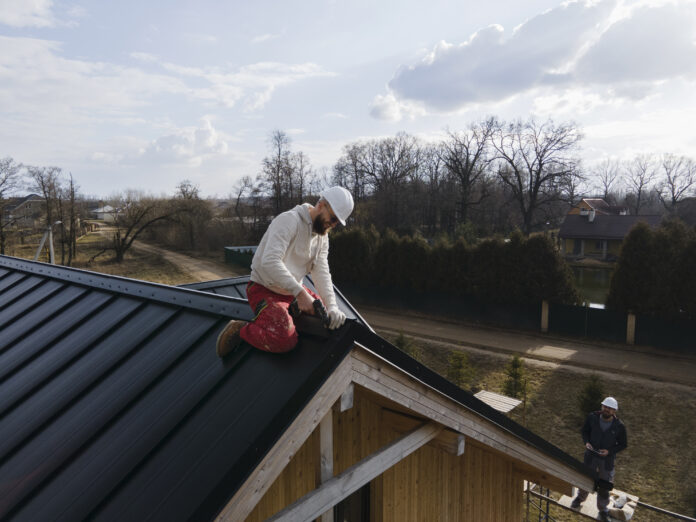 homeowner performing DIY roof repair, replacing shingles, and sealing leaks with tools on a sunny day.