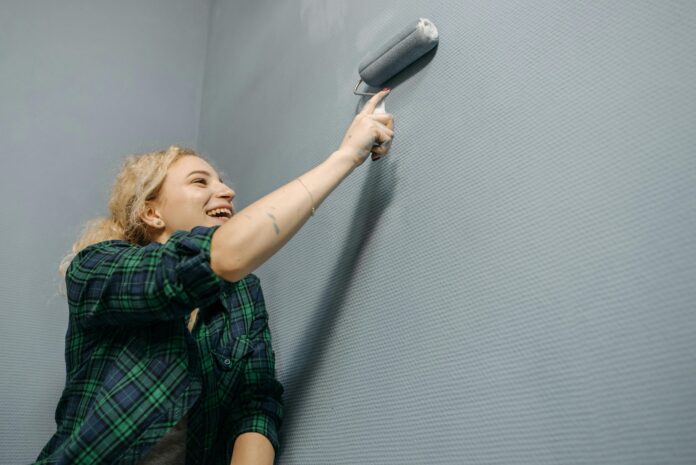 Hands repairing paint issues on a wall with a brush and putty, achieving a smooth, flawless surface.